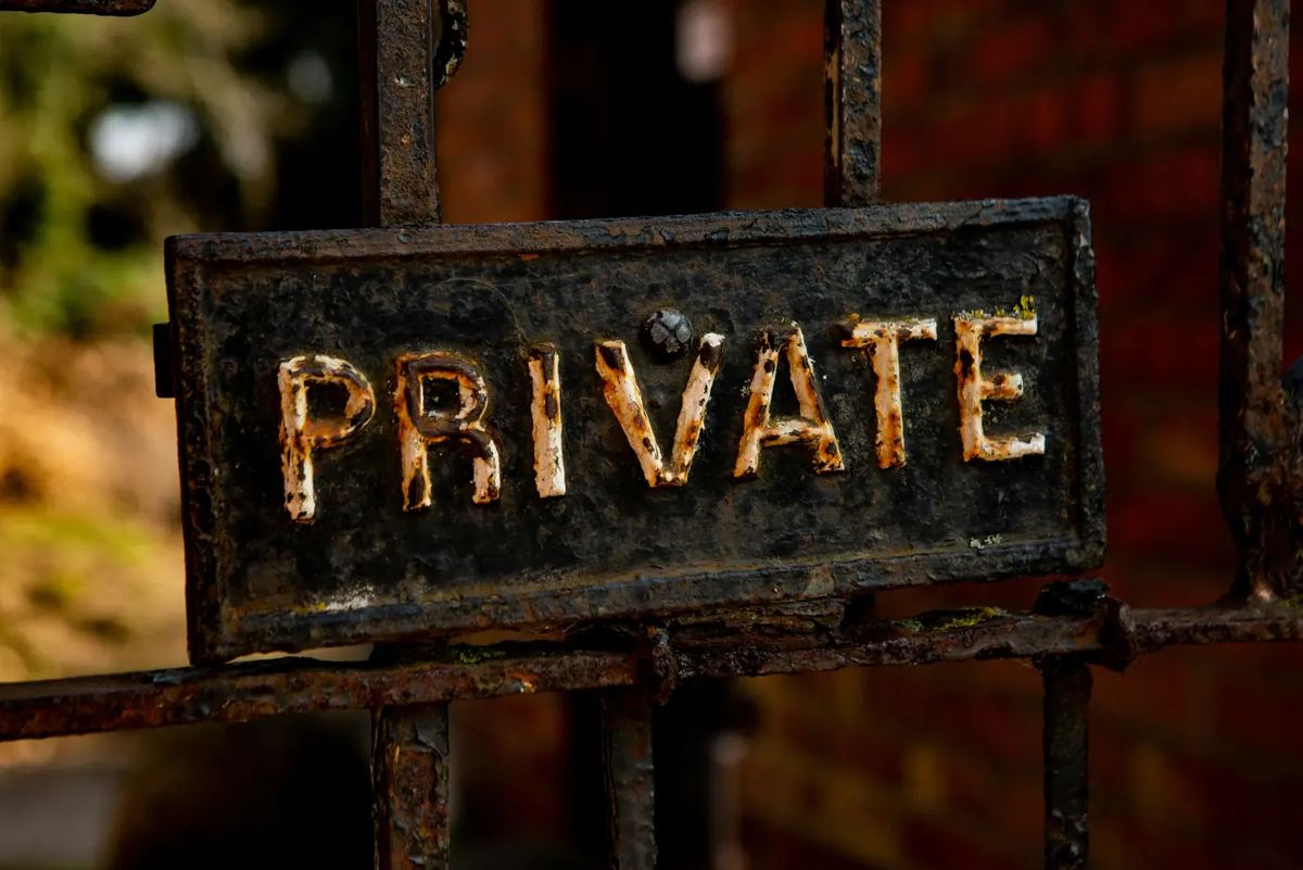A weathered cast-iron gate sign reading PRIVATE
