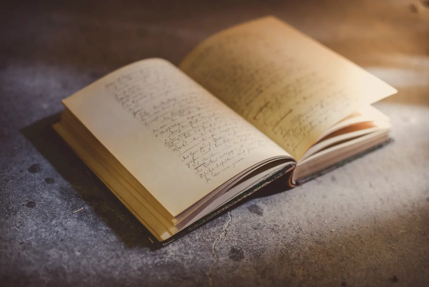An old handwritten book lying open, its pages full of faded ink
