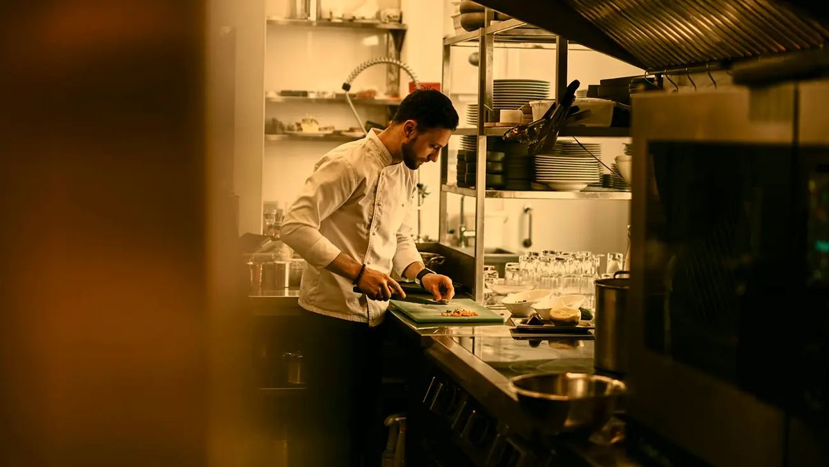 A chef working at a counter in an open restaurant kitchen