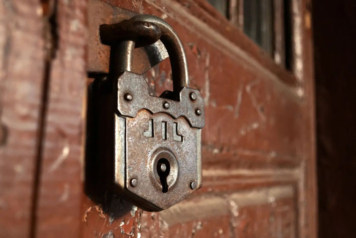 An old iron padlock hanging on a red-painted wooden door